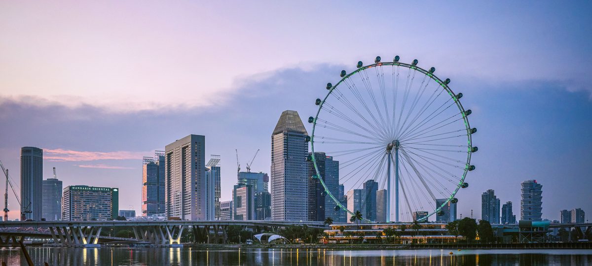 The Singapore Flyer and the Marina Bay skyline reflected in the water at dusk.